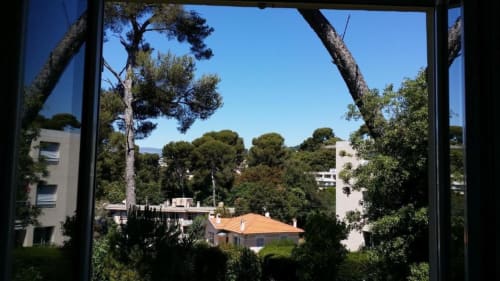 Vue depuis la fenêtre de la Résidence Kimi à Cannes sur une villa méditerranéenne, les pins et le ciel bleu azur