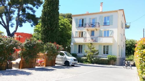 Hôtel Kimi Résidence à Cannes avec bâtiment crème, volets bleus et voiture blanche garée devant
