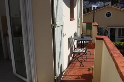 Terrasse de l'hôtel Kimi Résidence à Cannes avec table, chaises et vue mer sur l'architecture méditerranéenne