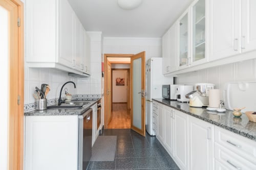 Modern white kitchen with granite countertops and wooden doors at EcoHost in Perafita, Portugal