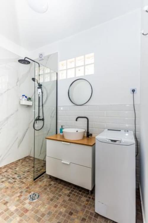 Baño moderno en Smart Rent Fuerteventura con ducha a ras de suelo, espejo redondo, tocador blanco y lavadora