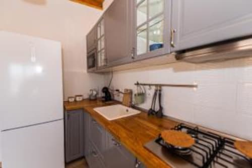 Cocina moderna con encimeras de madera, estufa de gas, fregadero y muebles grises en Smart Rent Fuerteventura