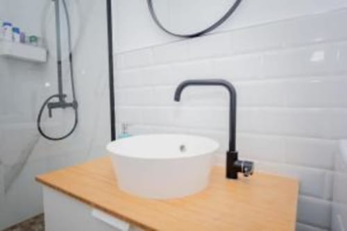 Moderno lavabo de baño con grifo negro y lavamanos de cerámica blanca en apartamento Smart Rent Fuerteventura, Tarajalejo