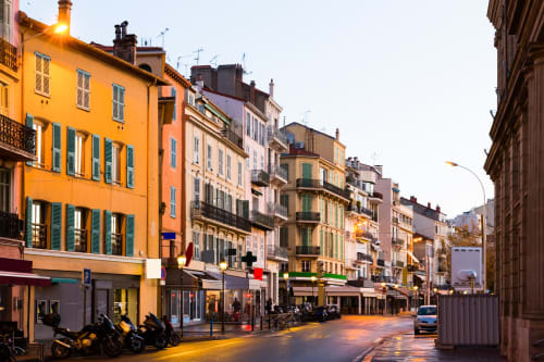 Rue colorée du centre de Cannes avec bâtiments historiques, boutiques et éclairage en soirée près de l'hôtel Kimi Résidence
