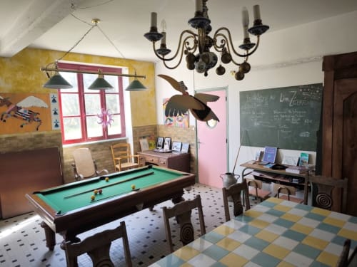 Colorful game room at Le Lama Zébré with billiards table, checkered floor, and decorative bird sculpture