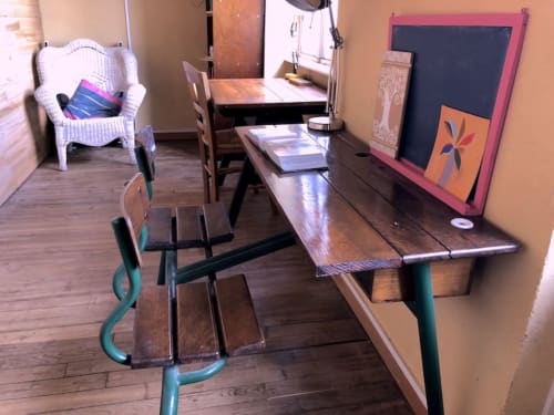 Shared common area at Le Lama Zébré with dining table, chairs, wicker seating, and games in Penmarch