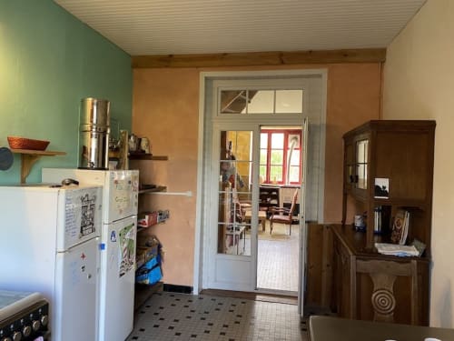 Kitchen area at Le Lama Zébré B&B in Penmarch with refrigerator, stove, and wooden cabinet furniture.