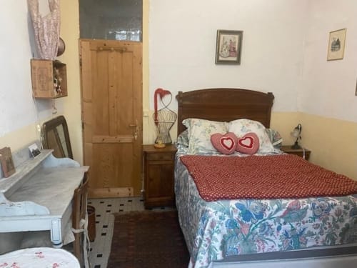 Cozy bedroom at Le Lama Zébré B&B in Penmarch with wooden bed, vintage decor, and heart pillows