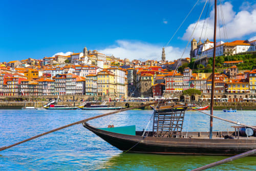 Traditional boats on Douro River with colorful Porto cityscape and architecture in background