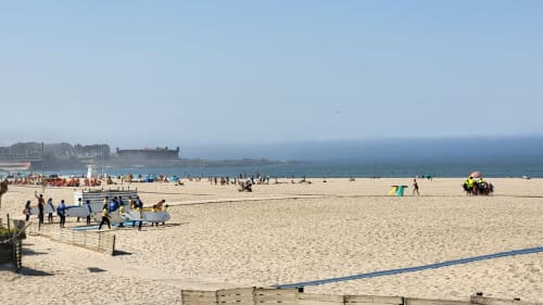 Beach volleyball tournament at Perafita with sandy beach, colorful tents, and fortress in background