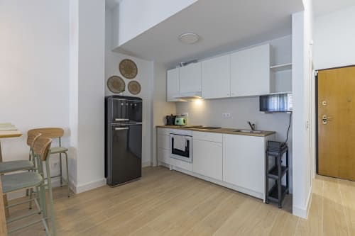 Cocina moderna con armarios blancos, horno negro y comedor en el apartamento del Numidas Open House Hotel, Murcia