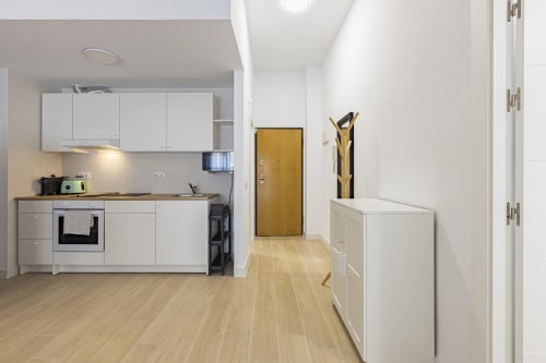 Cocina abierta y sala de estar moderna del Numidas Open House Hotel en Murcia, con mueblería blanca y piso de madera