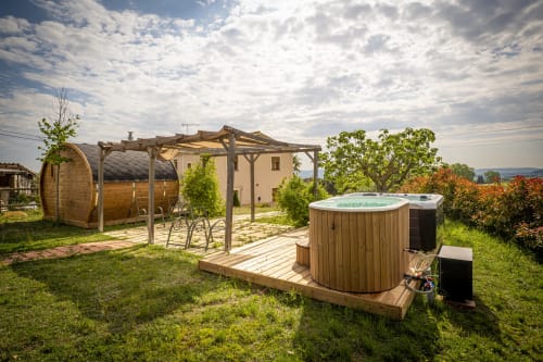 Cal Magí hotel outdoor area with wooden hot tub, pergola, and barrel sauna in Guardiola de Font Rubi, Spain
