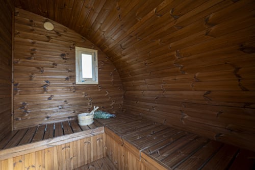 Wooden sauna interior at Cal Magí hotel with benches, window, and traditional bucket in Guardiola de Font Rubi