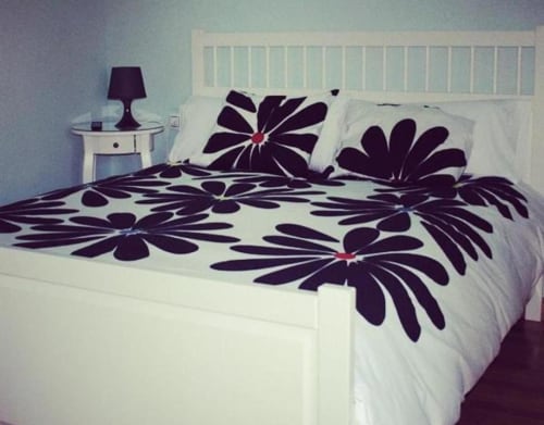 Dormitorio en Casas Rurales La Viña con cama blanca, edredón con estampado floral negro y lámpara de mesita