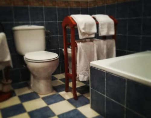 Baño de Casas Rurales La Viña con inodoro, bañera, toallero rojo, suelo de baldosas a cuadros y paredes de azulejos oscuros