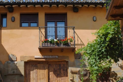 Balcón del apartamento La Viña 2 con flores rojas con vistas a Cuzcurrita de Río Tirón, España