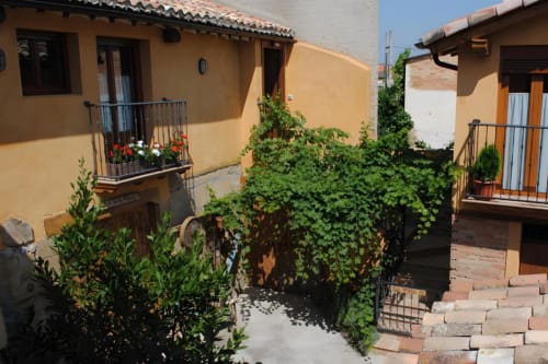 Patio de Casas Rurales La Viña con edificios de terracota, muros cubiertos de hiedra y balcones en Cuzcurrita de Río Tirón