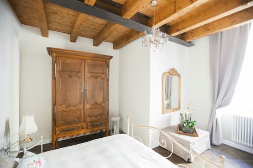 Elegant bedroom at Alessia's Place B&B in Como with wooden beams, antique wardrobe, and crystal chandelier