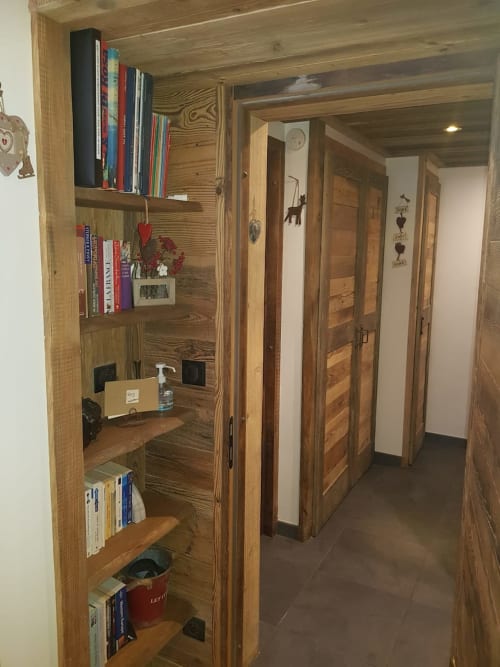 Couloir en bois du Zoppas Courchevel avec étagères intégrées, livres et portes donnant sur les suites