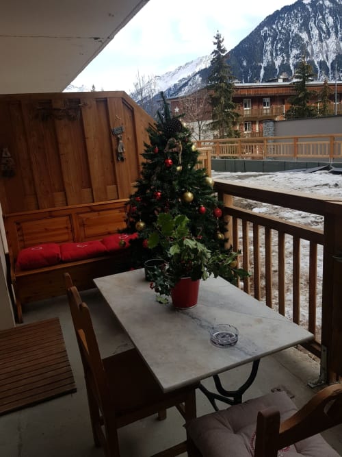 Balcon alpin à Zoppas Courchevel avec sapin de Noël décoré, mobilier en bois et vue sur les montagnes enneigées