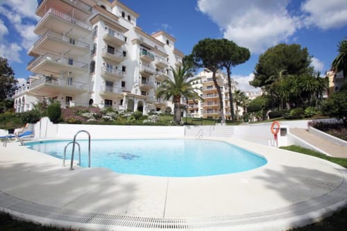 Oval swimming pool with terrace at Marbella Home Rentals apartment complex in Puerto Banús, Spain