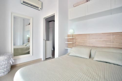 Modern bedroom in Marbella apartment with wood slat headboard, white bedding, and sea view at Puerto Banús
