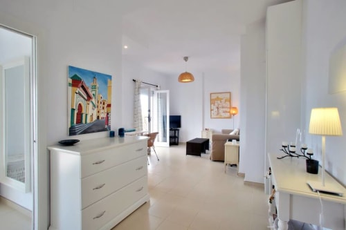 Bright Marbella apartment living room with white furniture, colorful artwork, and sea view access in Puerto Banús