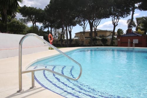 Crystal blue swimming pool with lane markers at Marbella Home Rentals, Puerto Banús, surrounded by Mediterranean trees