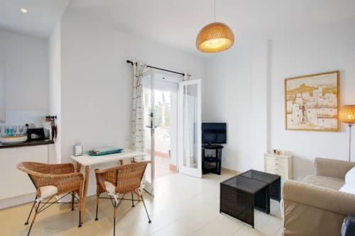 Bright Marbella apartment living room with wicker chairs, beige sofa, and sea view access via terrace doors