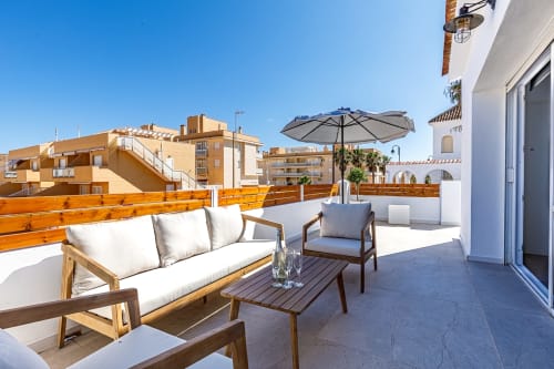 Terraza soleada en la azotea de Haus Holiday Homes en San Pedro del Pinatar con muebles de madera, sombrilla y vistas al Mediterráneo
