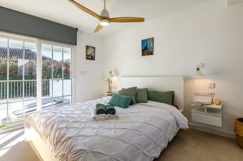 Dormitorio moderno en Haus Holiday Homes en San Pedro del Pinatar con vistas al balcón, ventilador de techo y detalles verdes