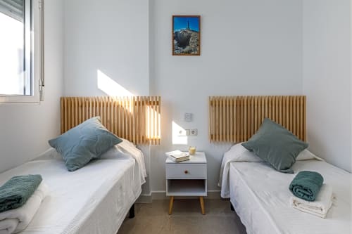 Habitación doble en Haus Holiday Homes, San Pedro del Pinatar, con cabeceros de madera, almohadas verdes y cuadros de montaña.