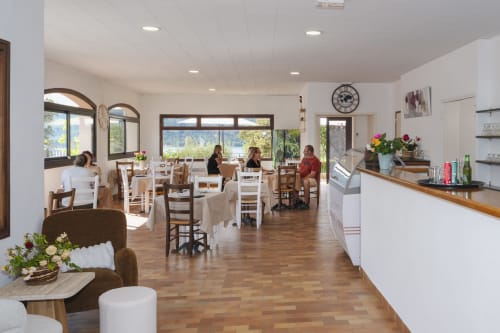 Salle à manger lumineuse de l'Hôtel Restaurant Le Verdon avec tables en bois, vue sur le lac et cheminée en pierre aux Salles sur Verdon