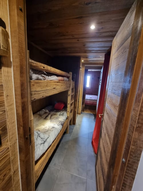 Lits superposés en bois rustique dans une chambre dortoir du Zoppas Courchevel, avec carrelage et éclairage chaleureux