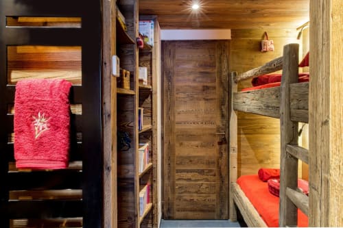 Lits superposés rustiques avec literie rouge au refuge alpin Zoppas Courchevel, avec rangements et éclairage chaleureux