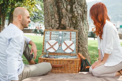 Couple enjoying a picnic with basket by a tree at Alessia's Place, Como, Italy