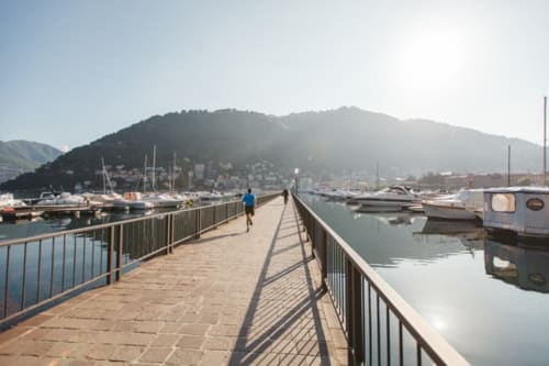Wooden pier at Alessia's Place B&B overlooking Lake Como with sailboats, mountains, and waterfront buildings in Como, Italy