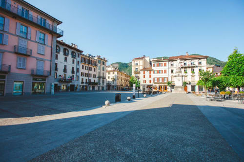 Historic Italian piazza in Como with colorful buildings, outdoor seating, and mountain views near Alessia's Place