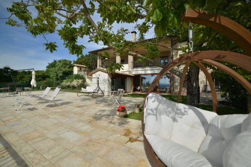 Esclusivo patio della Proprietà Clara ad Assisi con lettini, pergolato e villa in pietra con vista sulla campagna