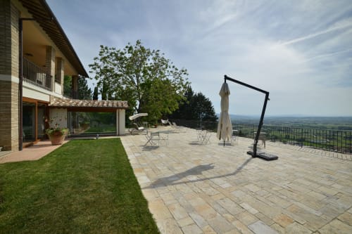 Terrazza Proprietà Clara ad Assisi con patio pavimentato, prato, ombrellone, sedute e vista sulla vallata