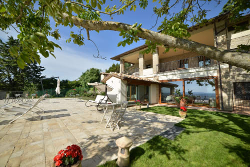 Terrazza Proprietà Clara ad Assisi con lettini, prato curato, piante fiorite e vista sulla campagna