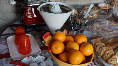 Tavolo della colazione a Proprietà Clara ad Assisi con arance fresche, candele rosse, spremiagrumi e pasticcini