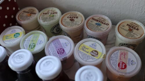 Collezione di contenitori di gelato italiano presso l'hotel Proprietà Clara ad Assisi, con gusti come caffè, nocciola e altri