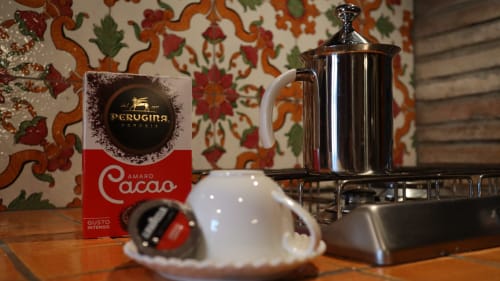 Scatola di cacao Perugina e caffettiera cromata sulla scrivania in legno dell'hotel Proprietà Clara ad Assisi