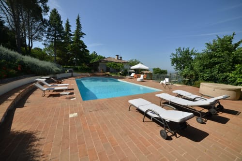 Piscina di Proprietà Clara ad Assisi con terrazza in cotto, lettini e vista sulla campagna