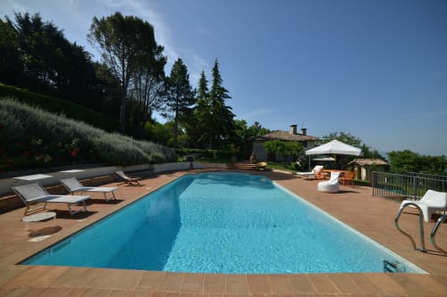 Piscina dell'hotel Proprietà Clara ad Assisi con lettini, terrazza e vista sulla campagna toscana