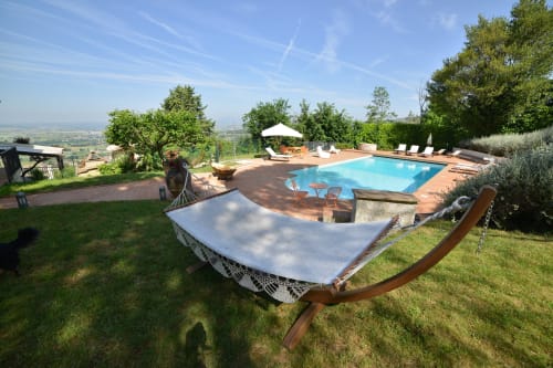 La piscina e l'amaca di Proprietà Clara con vista sulla valle di Assisi, ulivi e cielo azzurro