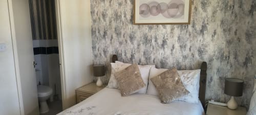Cozy double bedroom at The Sands Hotel, Paignton with textured wallpaper, comfortable bed with decorative pillows, and