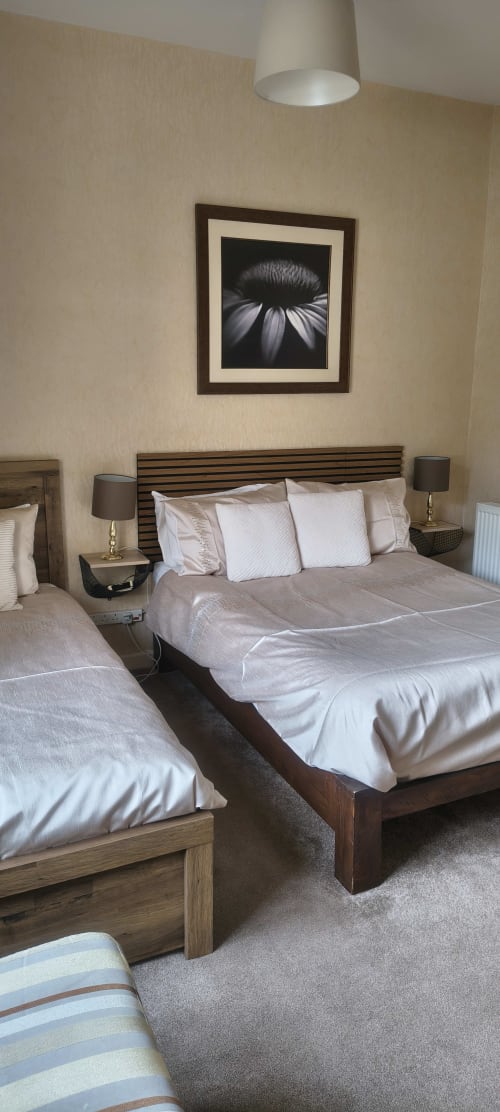 Triple Room at The Sands Hotel Paignton with two beds, dark wood headboards, white bedding, pendant lighting, and framed